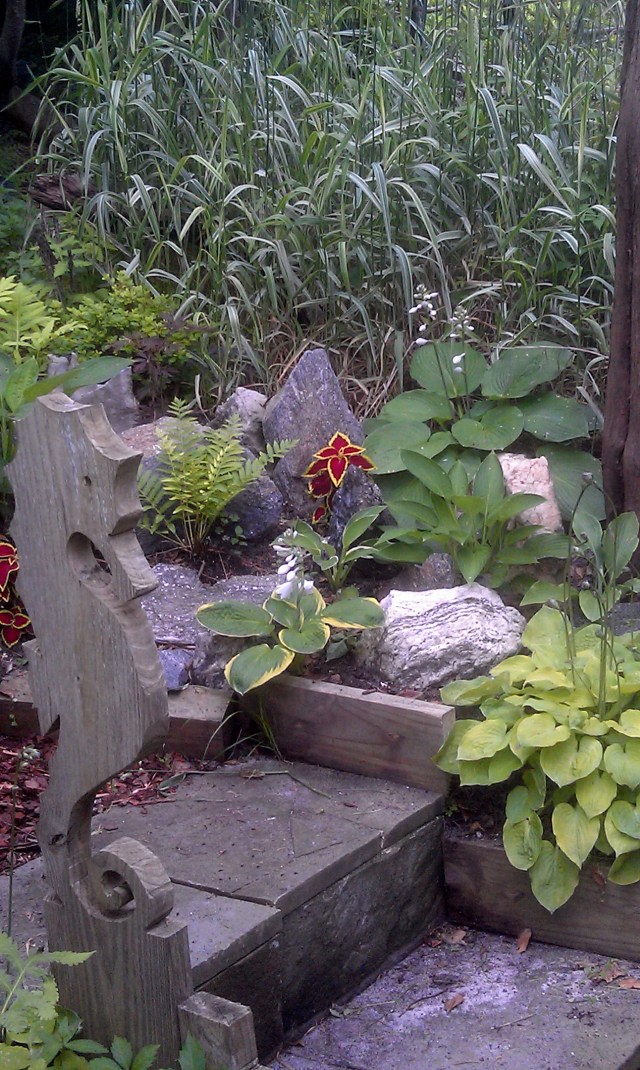 A close-up of the rock garden with varigated grasses behind and slate steps leading up from the hot tub patio.